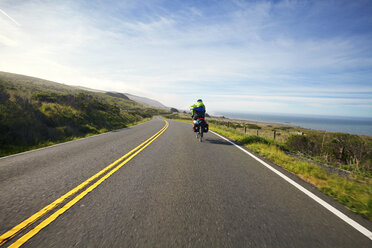 Rear view of cyclist on country road against sky - CAVF42298