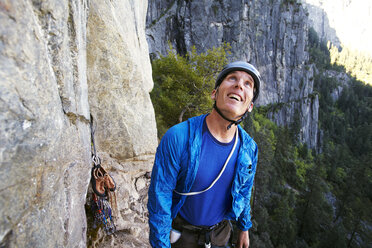 Glücklicher Mann, der nach oben schaut, während er an einer Felsformation vor einem Berg steht - CAVF42301