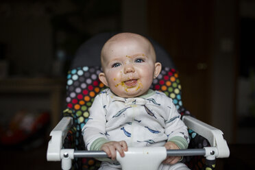 Cute Baby-Mädchen mit unordentlichen Gesicht schaut weg, während auf Hochstuhl zu Hause sitzen - CAVF42323