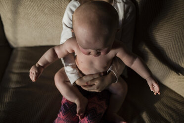 Midsection of girl with sister sitting on sofa at home - CAVF42333