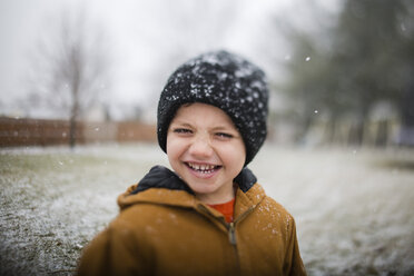 Porträt eines glücklichen Jungen, der im Winter auf einem Feld steht - CAVF42335