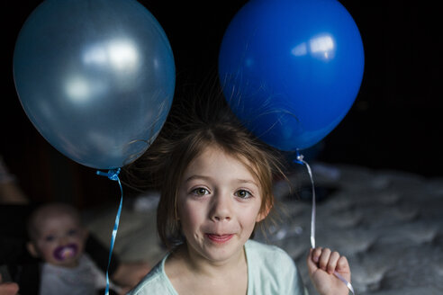 Porträt eines Mädchens, das Luftballons hält, während es zu Hause steht - CAVF42343