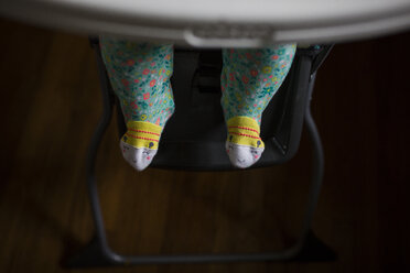 Niedriger Ausschnitt eines kleinen Mädchens, das zu Hause auf einem Hochstuhl sitzt - CAVF42358