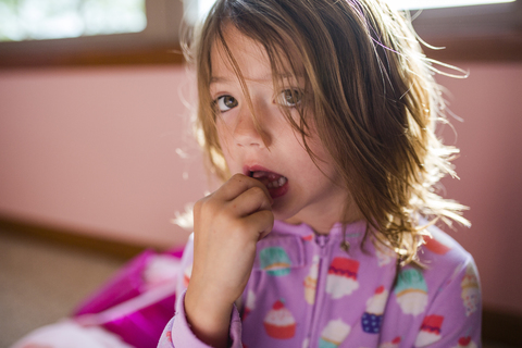 Porträt eines Mädchens, das zu Hause einen Zahn berührt, lizenzfreies Stockfoto