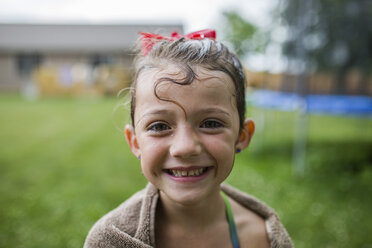 Portrait of happy girl wrapped in towel at yard - CAVF42395