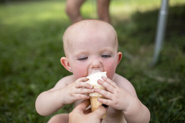 Cropped hand of mother feeding ice cream to daughter in yard - CAVF42400