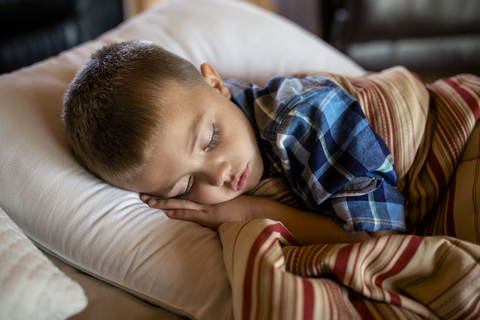 Hochformatiger Blick auf einen schlafenden Jungen zu Hause, lizenzfreies Stockfoto