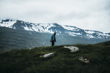 Mann steht auf einer Klippe vor schneebedeckten Bergen - CAVF42474