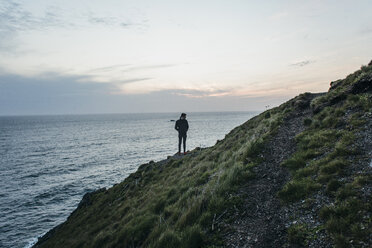 Wanderer steht auf einem Berg am Meer gegen den Himmel bei Sonnenuntergang - CAVF42483