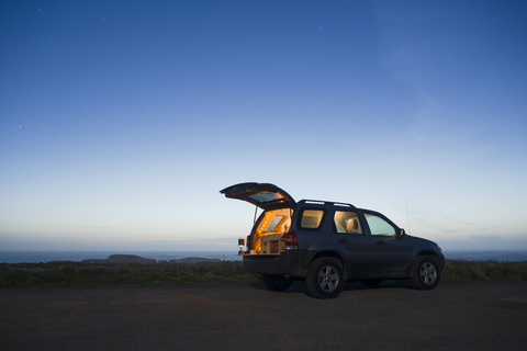 Auf einem Feld geparkter Geländewagen gegen den klaren Himmel in der Abenddämmerung, lizenzfreies Stockfoto