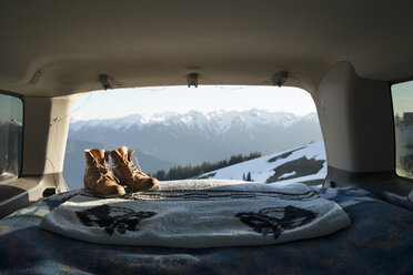Wanderschuhe und Decke in einem Geländewagen mit schneebedeckten Bergen im Hintergrund - CAVF42506