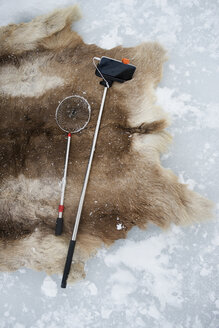 Hochwinkelansicht von Fischernetz und Einbeinstativ auf einem Teppich im Schnee im Abisko-Nationalpark - CAVF42521