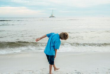 Rear view of playful boy bending at Panama City Beach against sky - CAVF42540