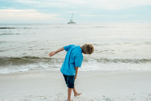 Rückansicht eines verspielten Jungen, der sich am Panama City Beach gegen den Himmel beugt - CAVF42540