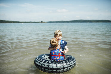 Brothers embracing in lake against sky - CAVF42550