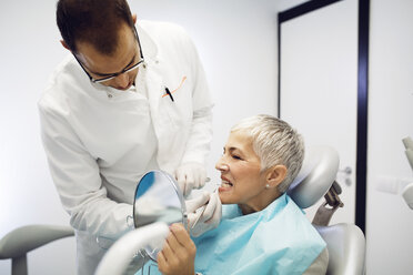 Dentist checking woman's teeth at clinic - CAVF42559