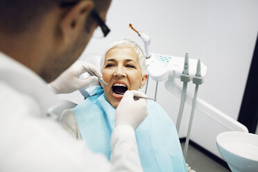 Männlicher Zahnarzt bei der Untersuchung der Zähne eines Patienten in der Klinik - CAVF42560
