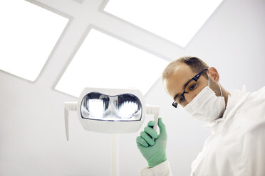 Niedrigwinkelansicht eines Zahnarztes, der eine Lampe in einer Klinik einstellt - CAVF42565