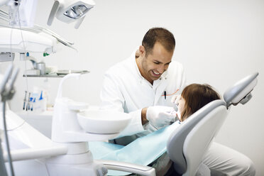 Lächelnder Zahnarzt untersucht die Zähne eines Mädchens in der Klinik - CAVF42577
