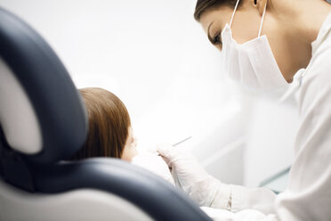 Zahnärztin mit chirurgischer Maske bei der Untersuchung eines Mädchens in einer Klinik - CAVF42582