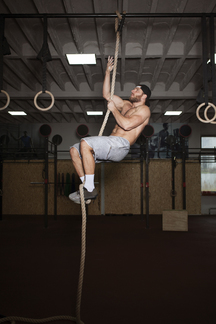 Man climbing on rope while exercising in gym stock photo