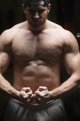 Vorderansicht eines Sportlers mit muskulösem Körperbau, der im Fitnessstudio steht - CAVF42600
