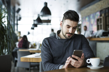 Mann benutzt Smartphone in einem Cafe - CAVF42623