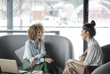 Lächelnde Geschäftsfrauen, die im Restaurant diskutieren - CAVF42640