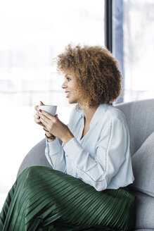 Businesswoman having coffee while sitting on sofa at restaurant - CAVF42641
