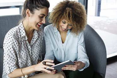 Cheerful female colleagues using tablet computer at cafe - CAVF42642