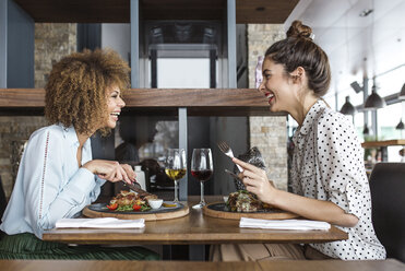 Cheerful businesswomen having lunch at table in restaurant - CAVF42644