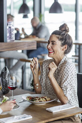 Fröhliche Geschäftsfrau, die einen Kollegen beim Mittagessen im Restaurant ansieht - CAVF42646