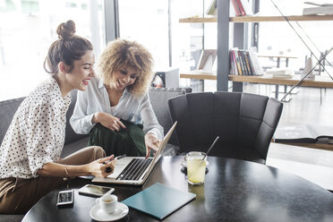 Happy business colleagues using laptop at table in restaurant - CAVF42647