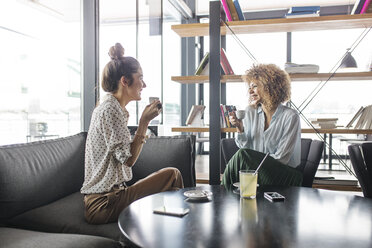 Happy businesswomen discussing while having coffee at cafe - CAVF42649