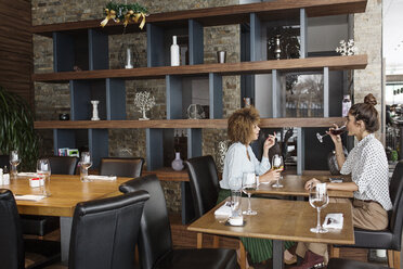 Geschäftsfrauen trinken Wein, während sie am Tisch im Restaurant sitzen - CAVF42680