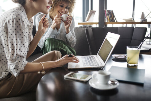 Geschäftsfrauen arbeiten an einem Laptop im Restaurant - CAVF42684