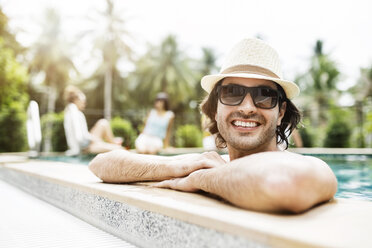 Glücklicher Mann entspannt sich im Schwimmbad eines Ferienortes - CAVF42716