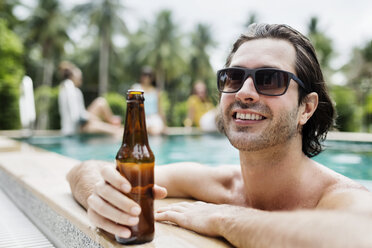 Nachdenklicher Mann mit Bierflasche im Schwimmbad - CAVF42717