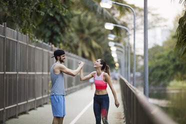 Smiling couple holding hands while jogging at park - CAVF42728