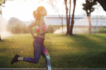 Side view of woman jogging at park on sunny day - CAVF42764