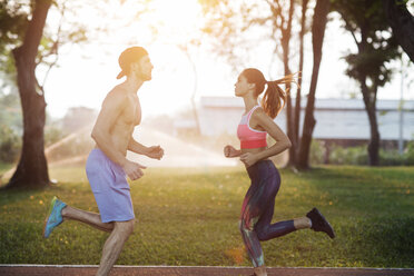 Side view of couple exercising at park on sunny day - CAVF42765