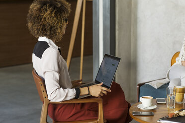 Side view of businesswoman with laptop sitting at hotel lobby - CAVF42781