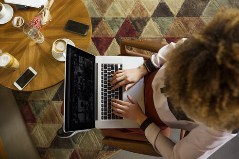 Draufsicht auf eine Geschäftsfrau, die einen Laptop in einer Hotellobby benutzt - CAVF42787