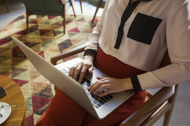 Mittelteil einer Geschäftsfrau mit Laptop in einer Hotellobby - CAVF42788