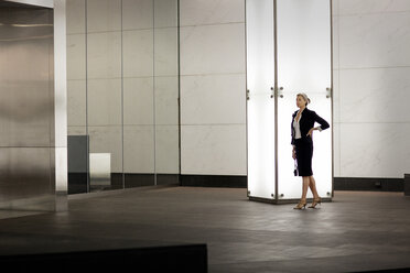 Confident businesswoman standing by illuminated blank column in city - CAVF42847