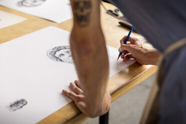 Cropped image of man drawing sketch while standing in workshop - CAVF42941