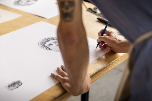 Ausgeschnittenes Bild eines Mannes, der in einer Werkstatt stehend eine Skizze zeichnet - CAVF42941