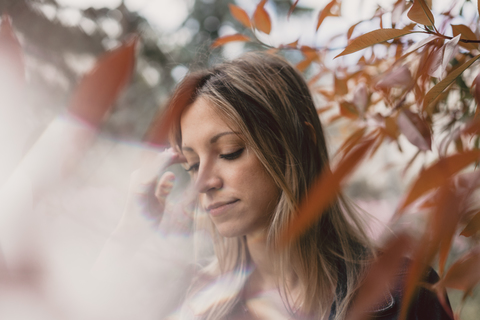 Portrait of young woman in between autumn leaves stock photo