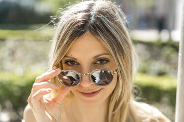 Porträt einer lächelnden jungen Frau mit verspiegelter Sonnenbrille - AFVF00444
