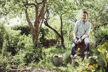 Happy young man relaxing while gardening at yard - MASF04931